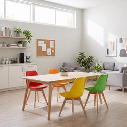A modern dining area with a light wood rectangular table surrounded by five colorful chairs in red, orange, yellow, and green, set in a bright, contemporary living space with a gray sofa and plants.
