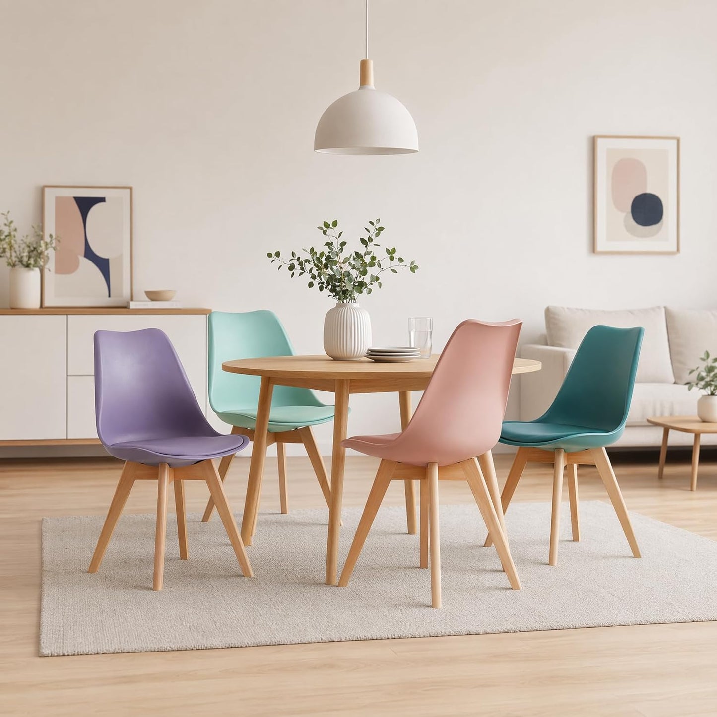 A dining set in a bright, modern room featuring a round wooden table and four molded plastic chairs in pastel purple, mint green, dusty pink, and teal, arranged on a light gray rug.